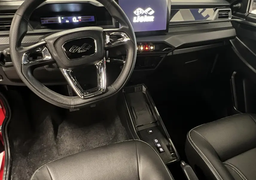 Vue intérieure avant du tableau de bord et volant noir du LIGIER JS50 BEV 8KWH ELITE avec écran tactile central allumé.