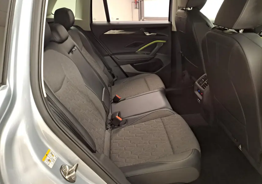 Vue intérieure arrière gauche du Volkswagen Tiguan 2025 argent Dolomite, sièges tissu et cuir avec console de climatisation arrière.