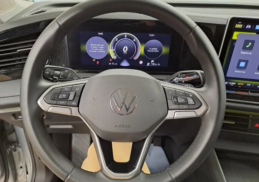 Vue rapprochée du volant multifonction noir du Volkswagen Tiguan 2025 avec tableau de bord numérique et écran tactile.