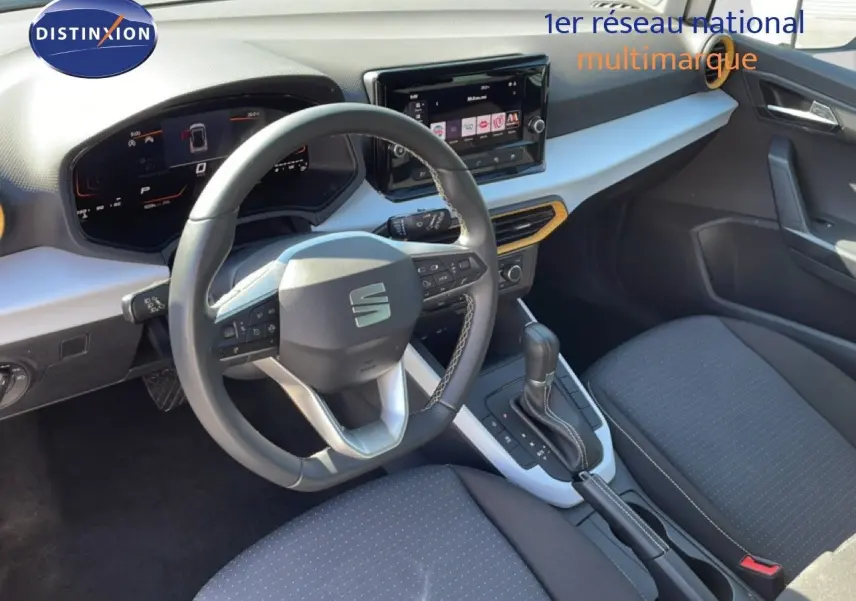 Vue intérieure côté conducteur du SEAT Arona 2025 blanc et gris, avec volant cuir multifonction et écran tactile central.