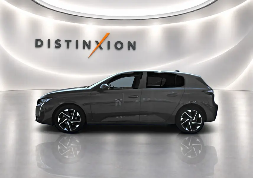 Profil côté gauche de la Peugeot 308 gris métallisé 2025 avec jantes alliage et vitres arrière surteintées dans un showroom.