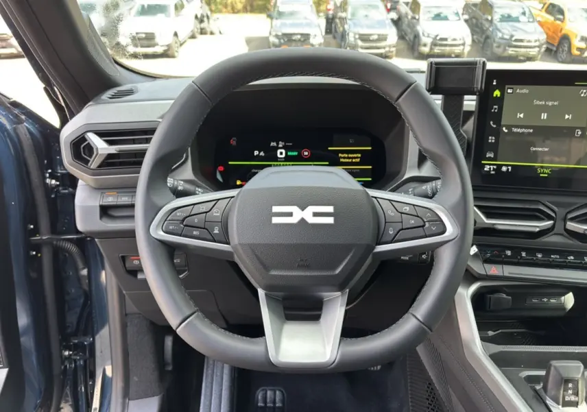 Vue intérieure centrée sur le volant cuir et le tableau de bord digital du Dacia Bigster Hybrid 155 bleu indigo.