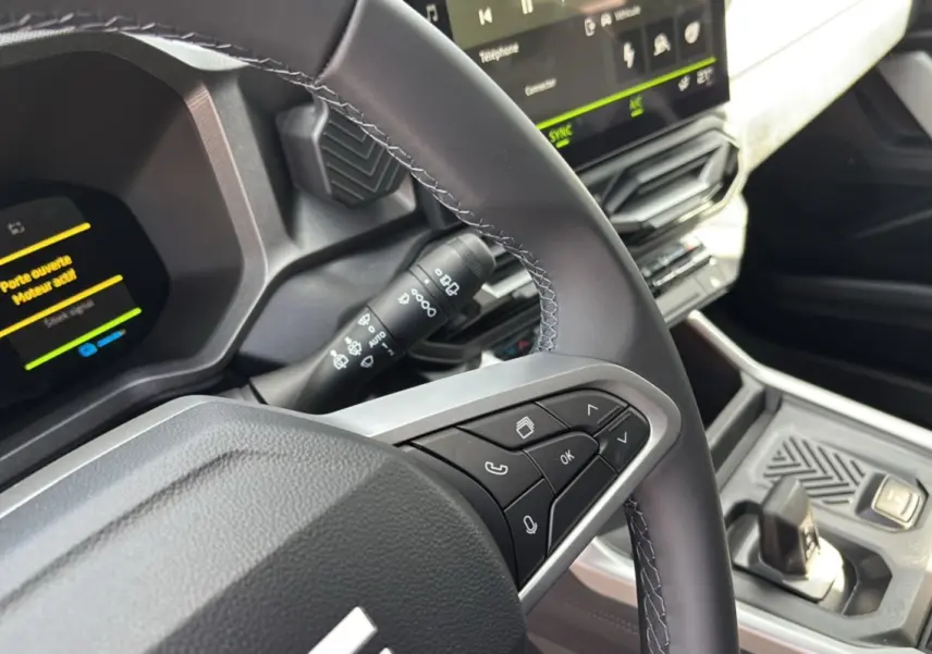 Gros plan sur le volant cuir et le tableau de bord digital du Dacia Bigster Hybrid 155, avec écran tactile et commandes au volant.