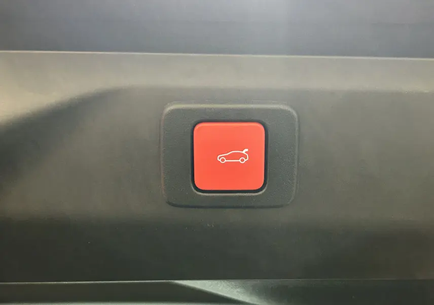 Bouton rouge d'ouverture électrique du hayon sur le panneau intérieur d'un Peugeot 3008 blanc Okenite.
