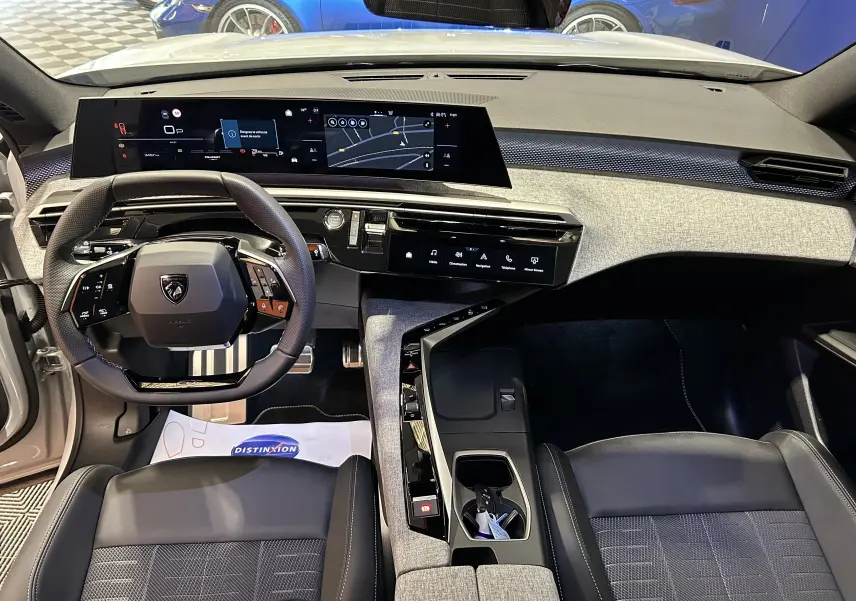 Vue intérieure avant du Peugeot 3008 blanc Okenite 2025, mettant en valeur le tableau de bord numérique et le volant multifonction.