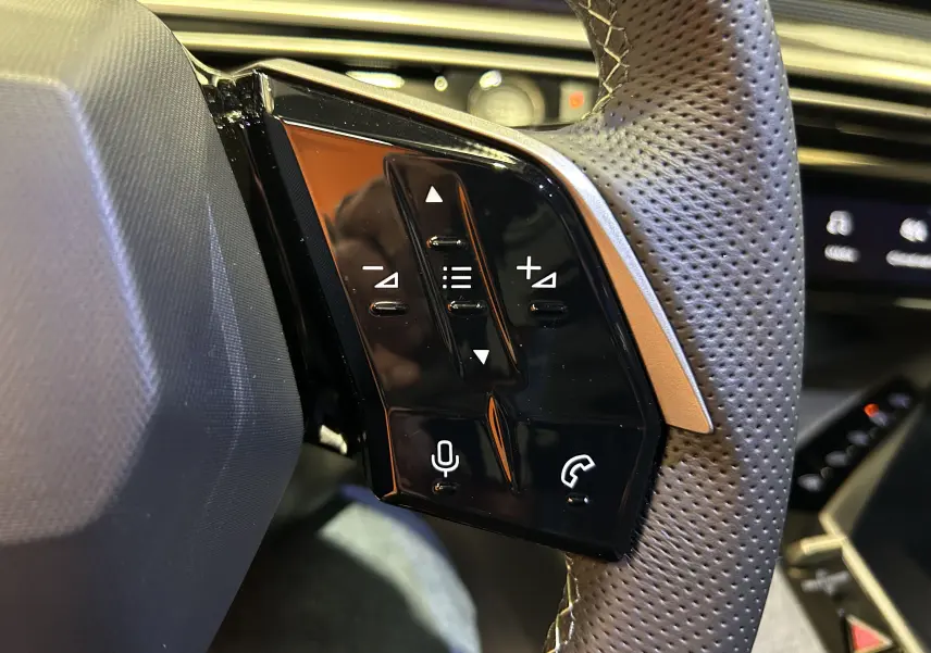Gros plan sur les commandes gauche du volant perforé du Peugeot 3008 blanc, avec boutons de volume et téléphone.