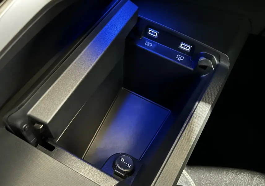Gros plan sur le compartiment central intérieur du Peugeot 3008 blanc, avec ports USB éclairés en bleu et prise 12V.