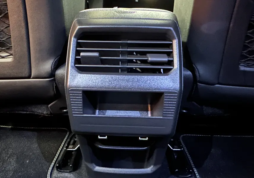 Vue rapprochée de la sortie d'air arrière centrale et des ports USB du Peugeot 3008 blanc Okenite, version hybride 2025.