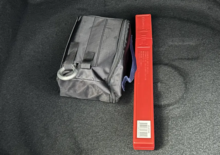 Coffre du Peugeot 3008 blanc avec trousse noire et triangle de signalisation rouge posé au sol.