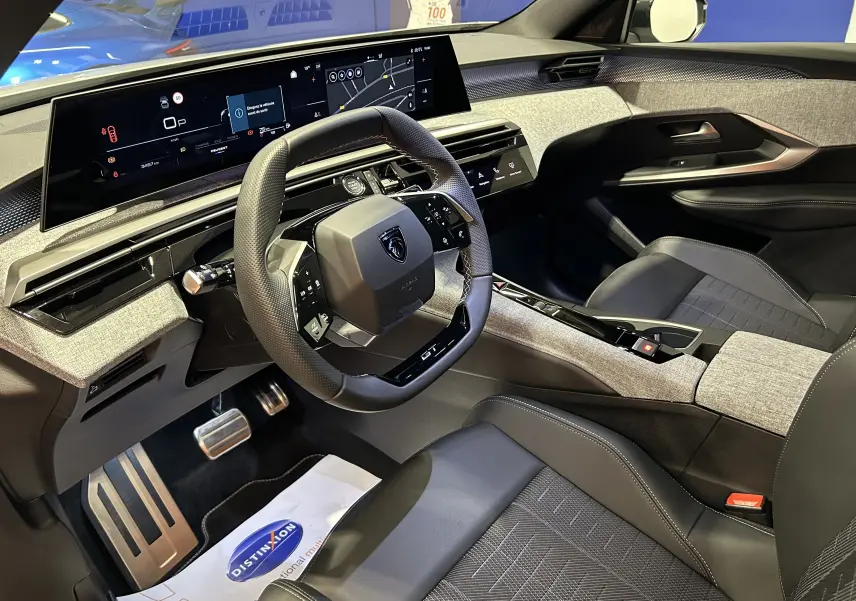 Vue intérieure côté conducteur du Peugeot 3008 III Hybrid 145 GT, avec tableau de bord numérique et finitions tissu gris et noir.