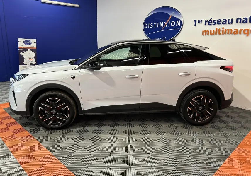 Vue de profil côté gauche d’un Peugeot 3008 blanc Okenite avec jantes noires et toit noir, en intérieur showroom.
