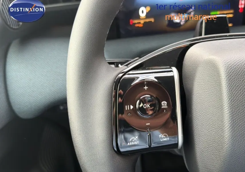 Gros plan sur la commande multifonction gauche du volant gris du Citroën C5 Aircross Hybrid 2026, avec affichage numérique en arrière-plan.