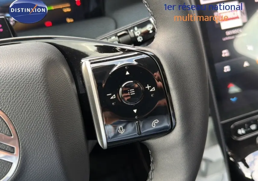 Gros plan sur les commandes gauche du volant en cuir noir du Citroën C5 Aircross Hybrid gris platinium, avec écran tactile en arrière-plan.