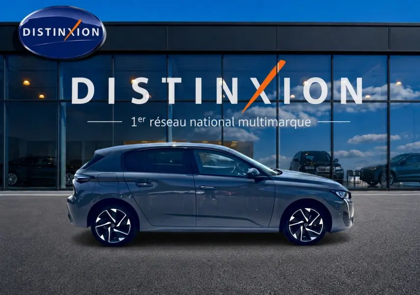 Profil côté gauche d'une Peugeot 308 gris 2025 avec jantes alu noires et design moderne devant une vitrine Distinxion.