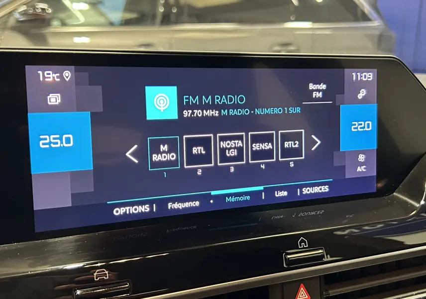 Écran tactile central affichant la radio FM dans l'habitacle d'une Citroën C4 orange, vue de face.