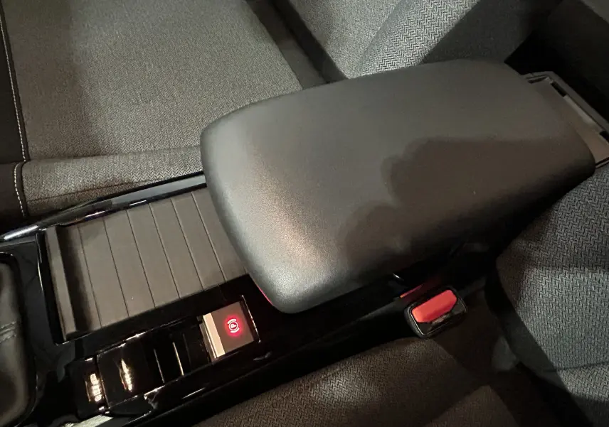 Gros plan sur l'accoudoir central noir et la console brillante avec frein à main électronique dans l'habitacle tissu gris d'une Citroën C4.