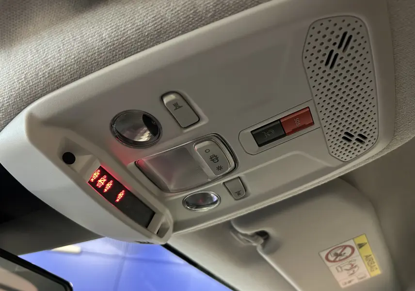 Vue en plongée sur le plafonnier gris clair de la Citroën C4 orange, avec boutons d'éclairage et alerte SOS visibles.