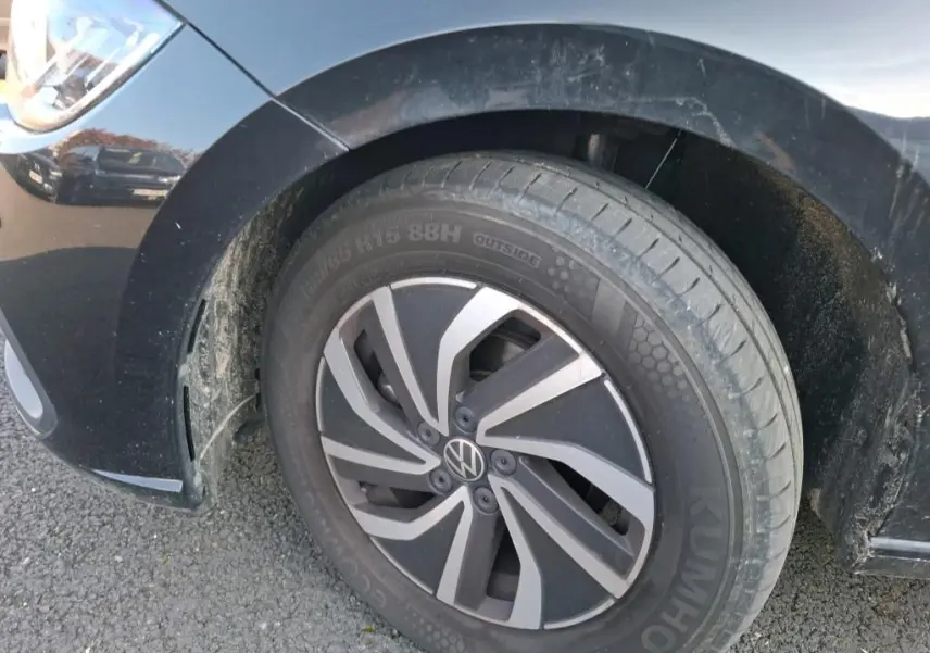 Gros plan sur la roue avant gauche noire d'une Volkswagen Polo 1.0 TSI 95 DSG7 Life avec jante alliage et carrosserie noire.