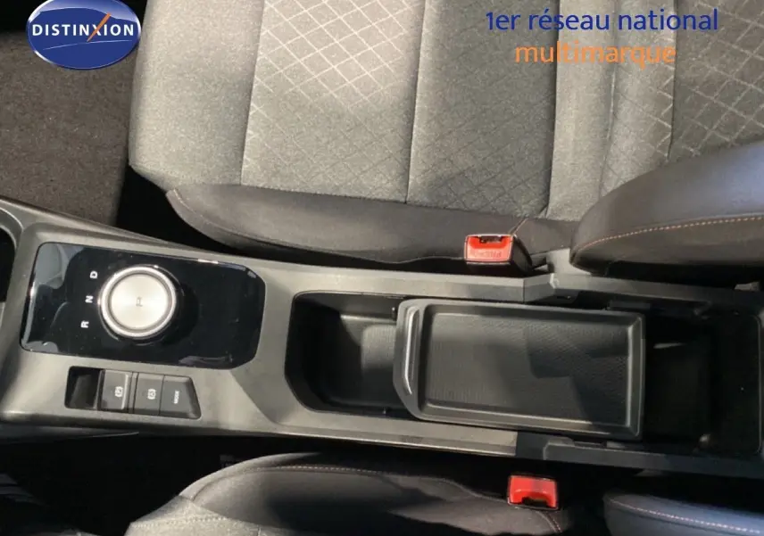 Vue intérieure centrée sur la console centrale et le levier rotatif de la MG3 1.5L Hybrid+ en tissu gris et noir.