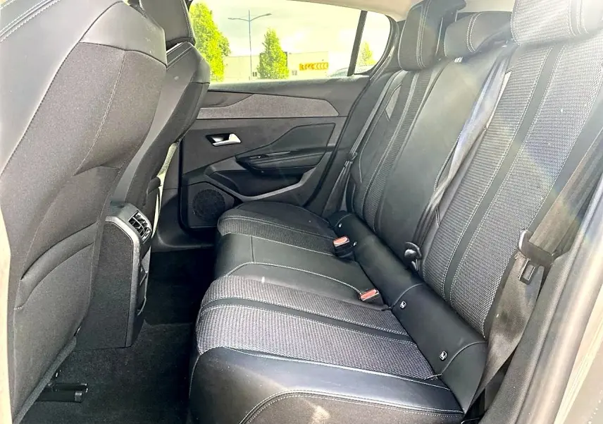 Vue latérale droite de l'habitacle arrière d'une Peugeot 308 gris, montrant la banquette et les appuie-têtes noirs.
