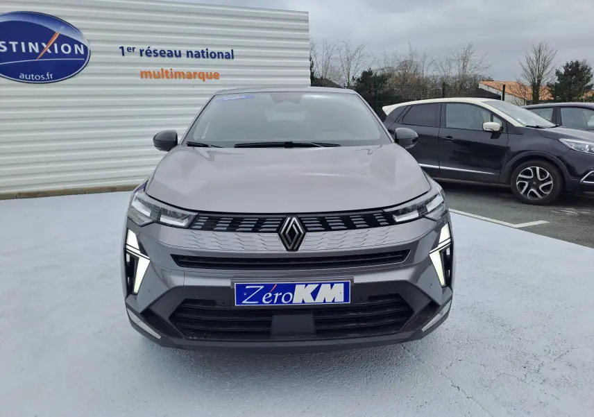 Vue frontale d'une Renault Symbioz gris Cassiope avec feux LED allumés sur un parking extérieur.