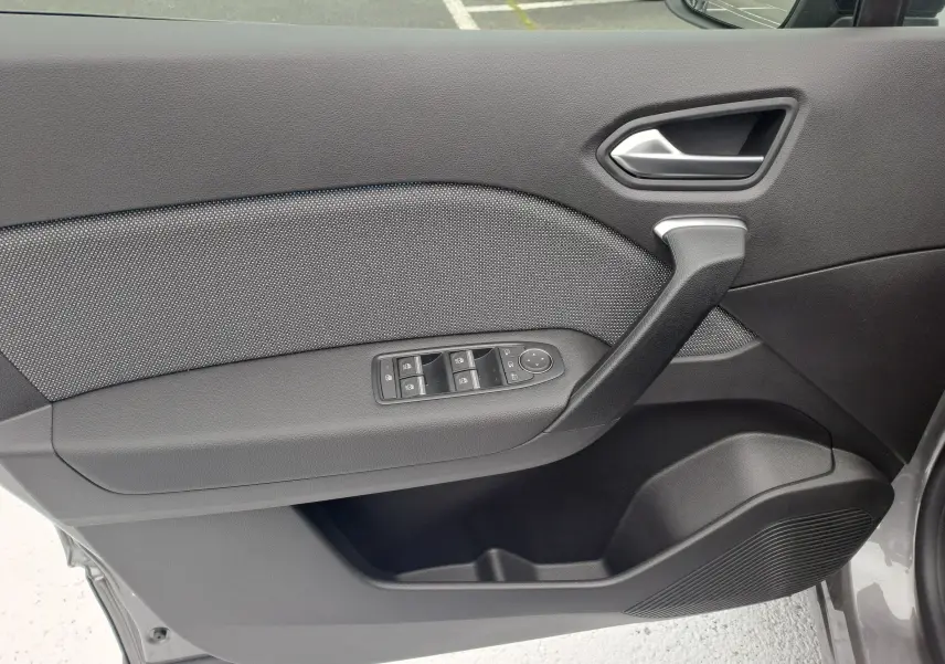 Intérieur côté gauche de la porte avant d'une Renault Symbioz gris Cassiope avec commandes électriques et poignée noire.