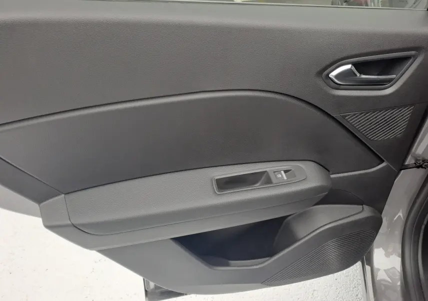 Intérieur côté gauche de la porte avant d'une Renault Symbioz gris Cassiope avec poignée argent et commande de vitre électrique.
