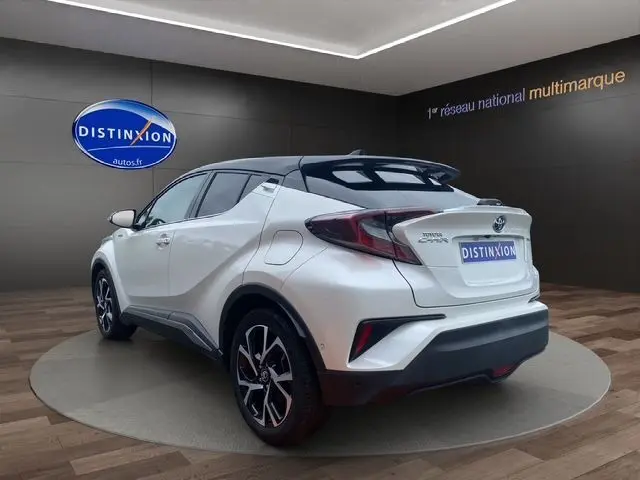 Toyota C-HR Hybride blanc toit noir en 3/4 arrière droit, mettant en valeur ses lignes dynamiques et ses jantes noires.