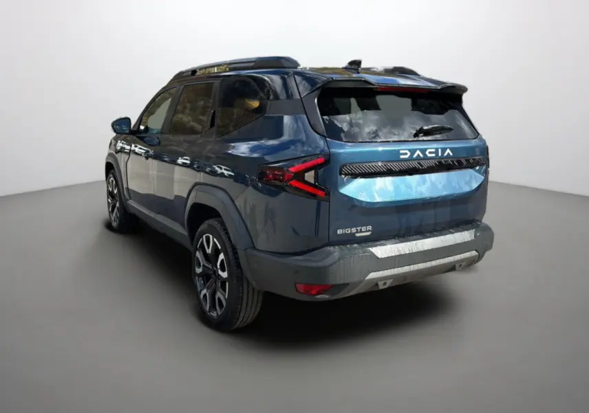 Vue 3/4 arrière gauche d'un Dacia Bigster bleu indigo avec toit noir et jantes alu 19 pouces dans un studio.