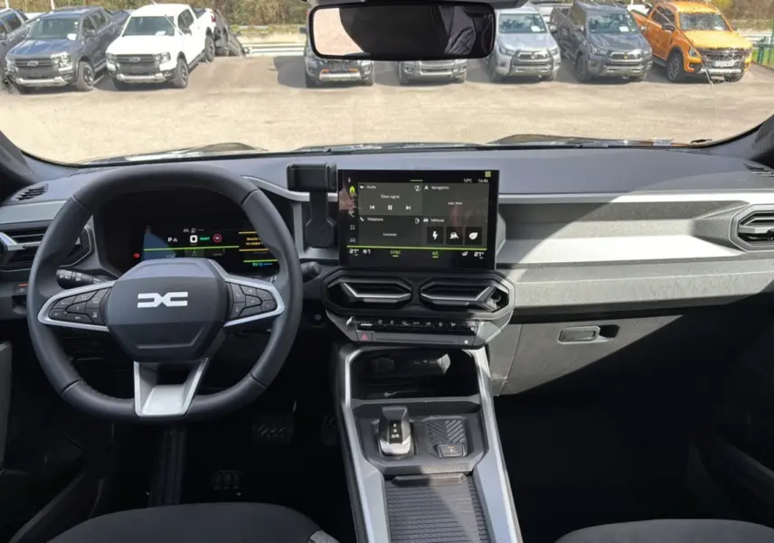 Vue intérieure du tableau de bord et volant cuir du Dacia Bigster Hybrid 155 Journey Plus avec écran tactile 10,1 pouces.