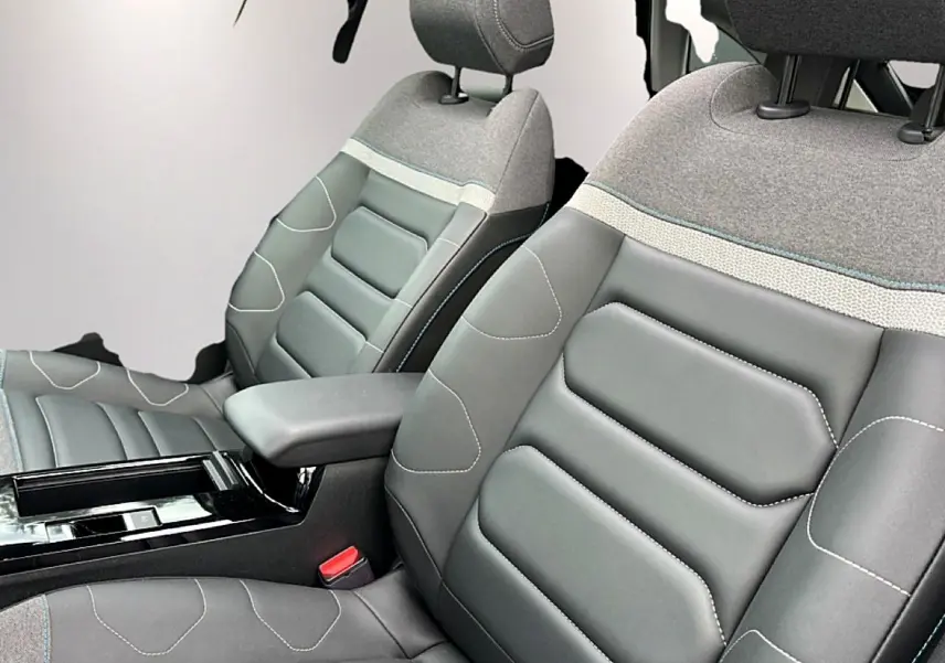 Gros plan sur les sièges avant gris cuir et tissu avec accoudoir central dans l'habitacle d'une Citroën C4 2024.