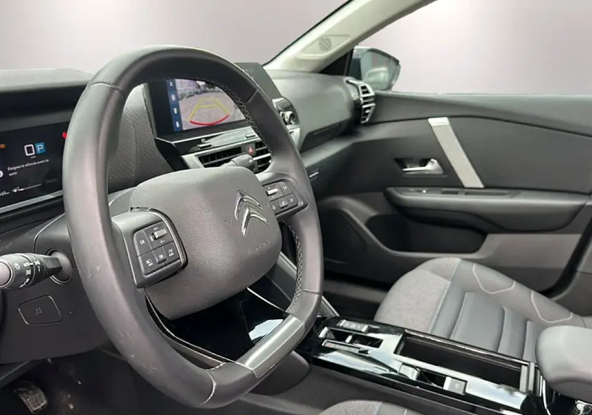 Intérieur de la Citroën C4 2024, vue côté conducteur sur le volant cuir et l’écran tactile avec caméra de recul.
