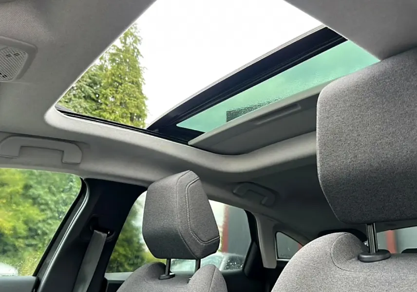 Vue intérieure montrant le toit ouvrant panoramique et les appuie-têtes avant en tissu gris d'une Citroën C4 2024.