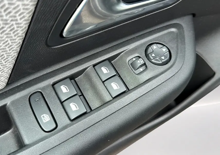 Gros plan sur les commandes de lève-vitres et rétroviseurs électriques côté conducteur d'une Citroën C4 gris 2024.