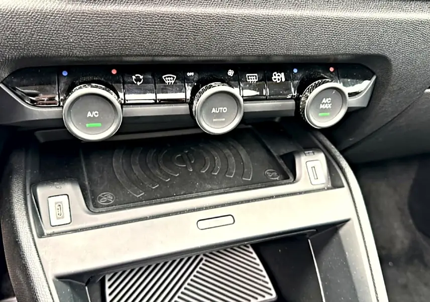 Détail de la console centrale avec commandes de climatisation et zone de recharge sans fil dans une Citroën C4 gris 2024.