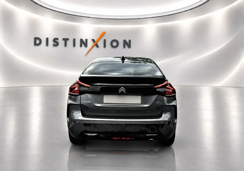 Vue arrière d'une Citroën C4 gris métallisé 2024, avec feux LED et logo distinctif sur fond blanc lumineux.