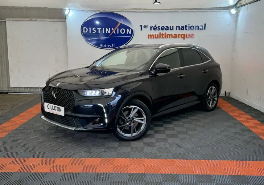 DS7 Crossback E-TENSE bleu en 3/4 avant droit, avec calandre distinctive et feux LED allumés dans un showroom.