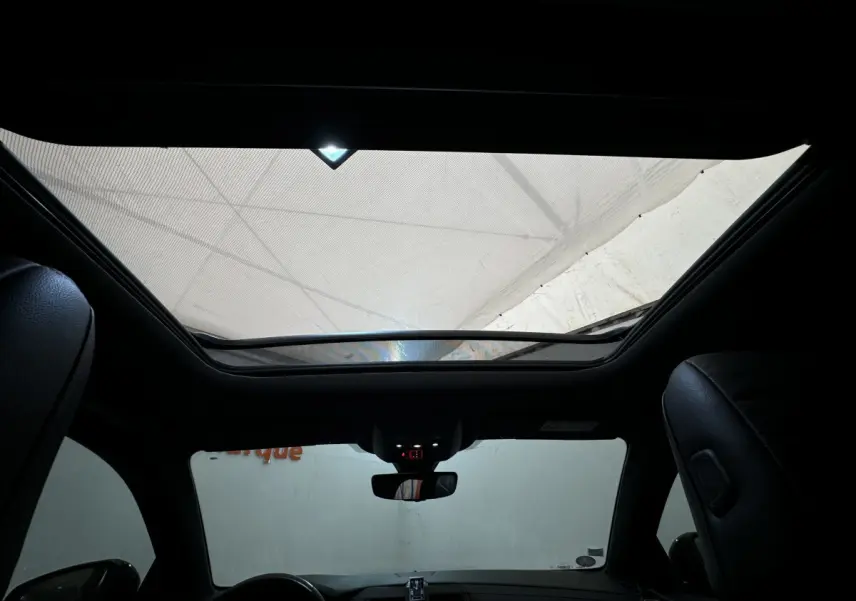 Vue intérieure du toit ouvrant panoramique et tableau de bord du DS7 Crossback E-TENSE 4x4 Grand Chic, sièges cuir noirs visibles.