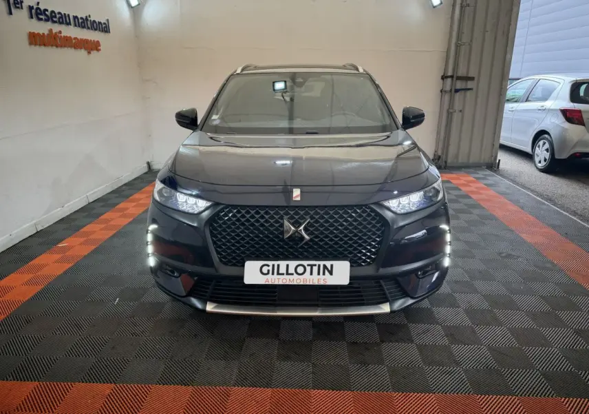 Vue frontale d'un DS7 Crossback E-TENSE 4x4 bleu avec calandre distinctive et feux LED allumés en intérieur.