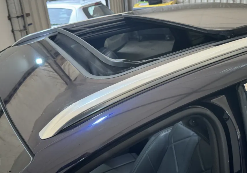 Vue rapprochée du toit ouvrant panoramique et du siège avant en cuir du DS7 Crossback E-TENSE bleu.