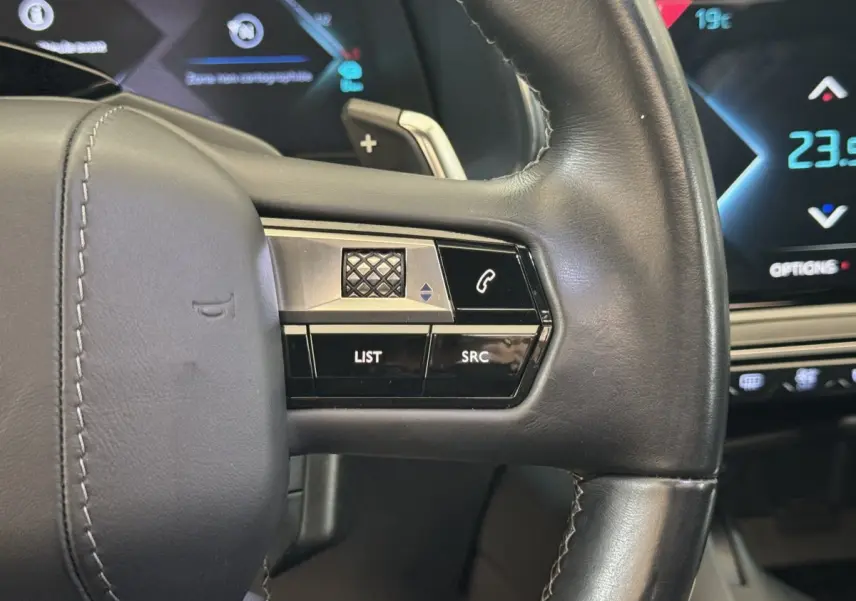 Gros plan sur le volant cuir noir du DS7 Crossback E-TENSE 4x4 Grand Chic avec commandes intégrées et affichage digital bleu.
