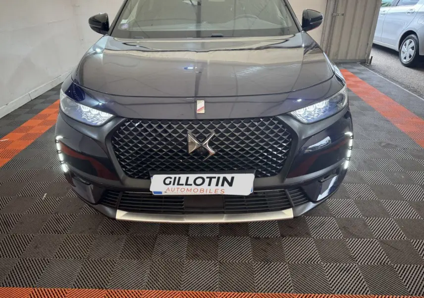 Vue frontale du DS7 Crossback E-TENSE bleu, mettant en valeur sa calandre distinctive et ses feux LED allumés.