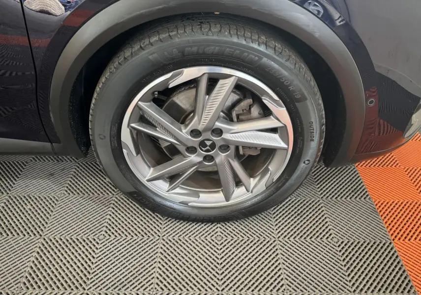 Gros plan sur la roue avant gauche bleu foncé du DS7 Crossback E-TENSE 4x4 avec jante alliage à cinq branches doubles.
