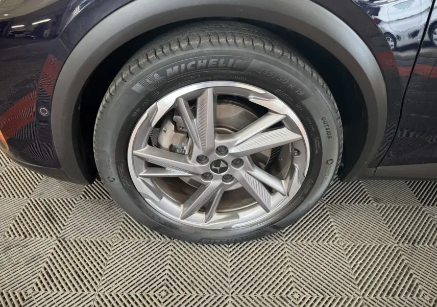 Gros plan sur la roue avant gauche bleue du DS7 Crossback E-TENSE 4x4 avec jante alliage et pneu Michelin.