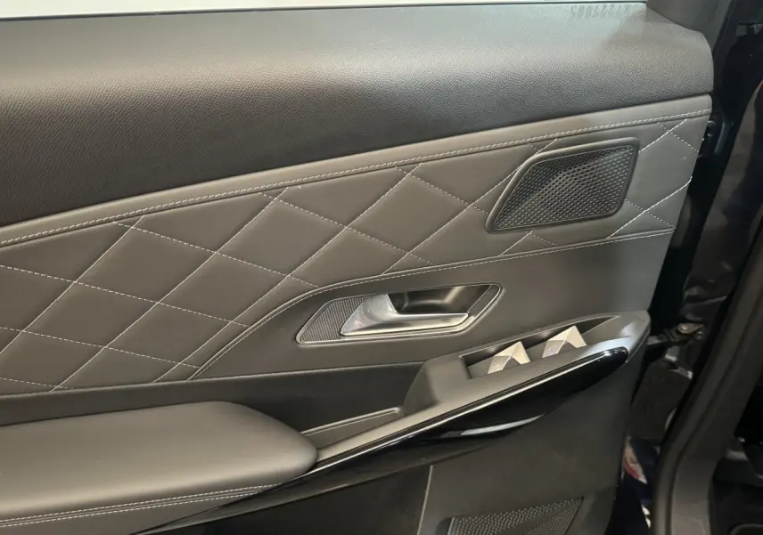 Gros plan sur la porte intérieure côté gauche du DS7 Crossback bleu, avec surpiqûres et commandes de vitres.