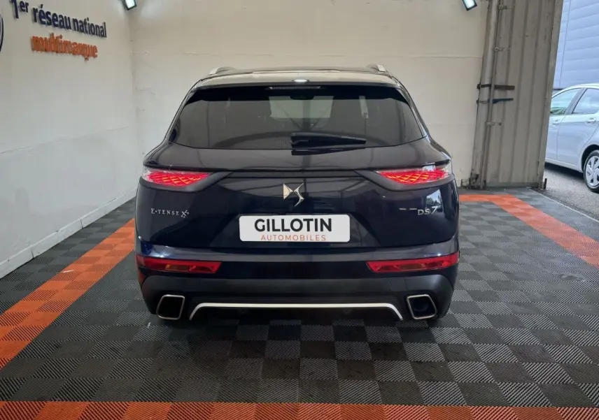 Vue arrière du DS7 Crossback E-TENSE bleu avec feux LED allumés et double sortie d'échappement carrée.