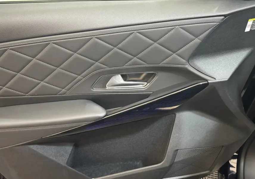 Gros plan sur la porte côté gauche du DS7 Crossback bleu, avec cuir matelassé et insert brillant à motifs géométriques.
