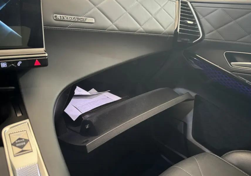 Intérieur du DS7 Crossback E-TENSE 4x4 Grand Chic 2020, vue sur boîte à gants ouverte et tableau de bord cuir noir matelassé.