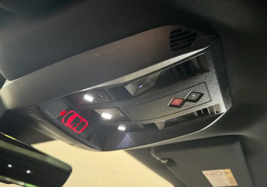 Vue en contre-plongée du panneau de commandes au plafond du DS7 Crossback bleu, avec éclairage et boutons SOS visibles.