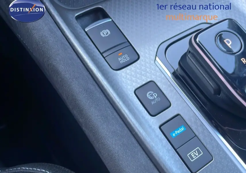 Gros plan sur la console centrale du Nissan Qashqai gris céramique, mettant en valeur les commandes de boîte automatique et modes de conduite électrique.